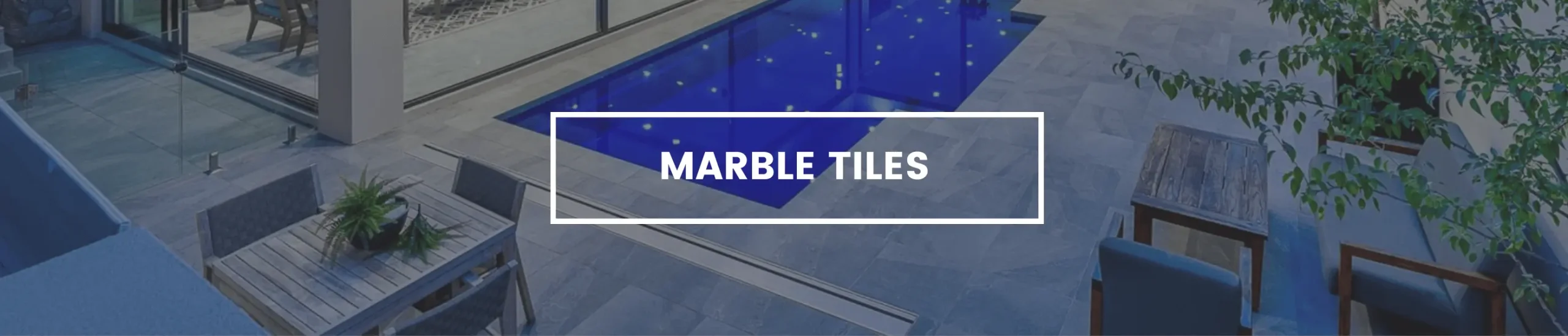 Marble tiles and pavers laid around a dark blue swimming pool.